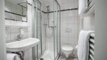 A modern bathroom with a glass-enclosed shower, a white sink, and a toilet.