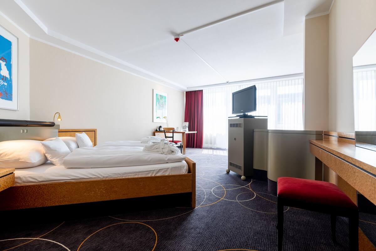 A hotel room with a bed, a desk, a television, and a chair.