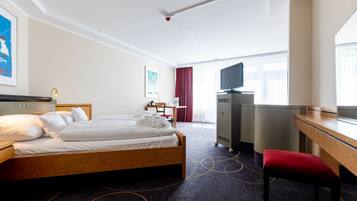 A hotel room with a bed, a desk, a television, and a chair.
