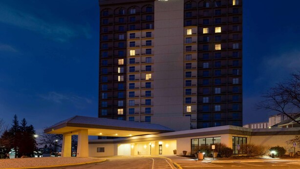 Ein mehrstöckiges Hotelgebäude mit einem gut sichtbaren 'La Quinta'-Schild, einer überdachten Einfahrt und einem Parkplatz.