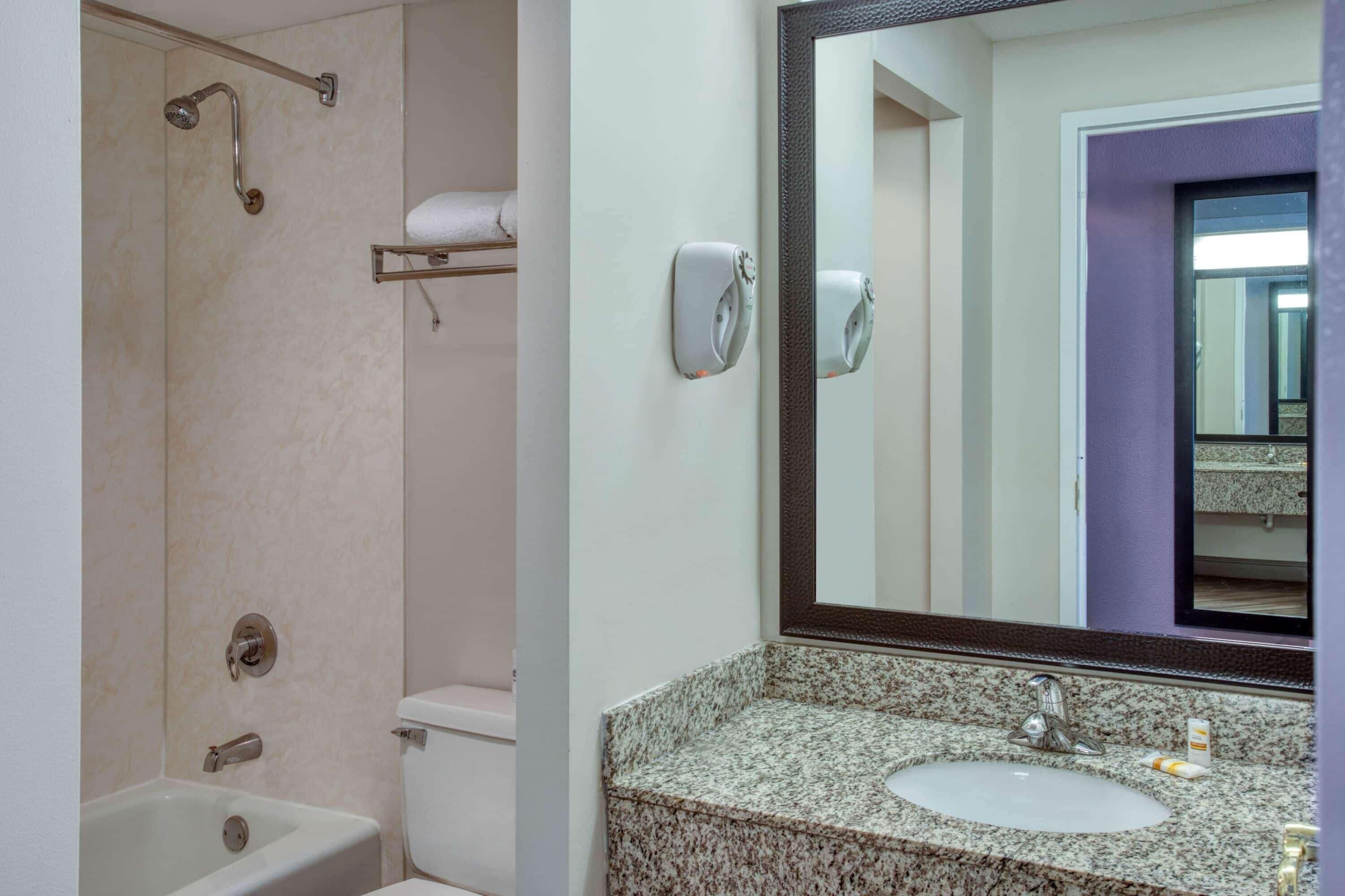 Une salle de bain équipée d’une douche, de toilettes, d’un lavabo et d’un grand miroir.