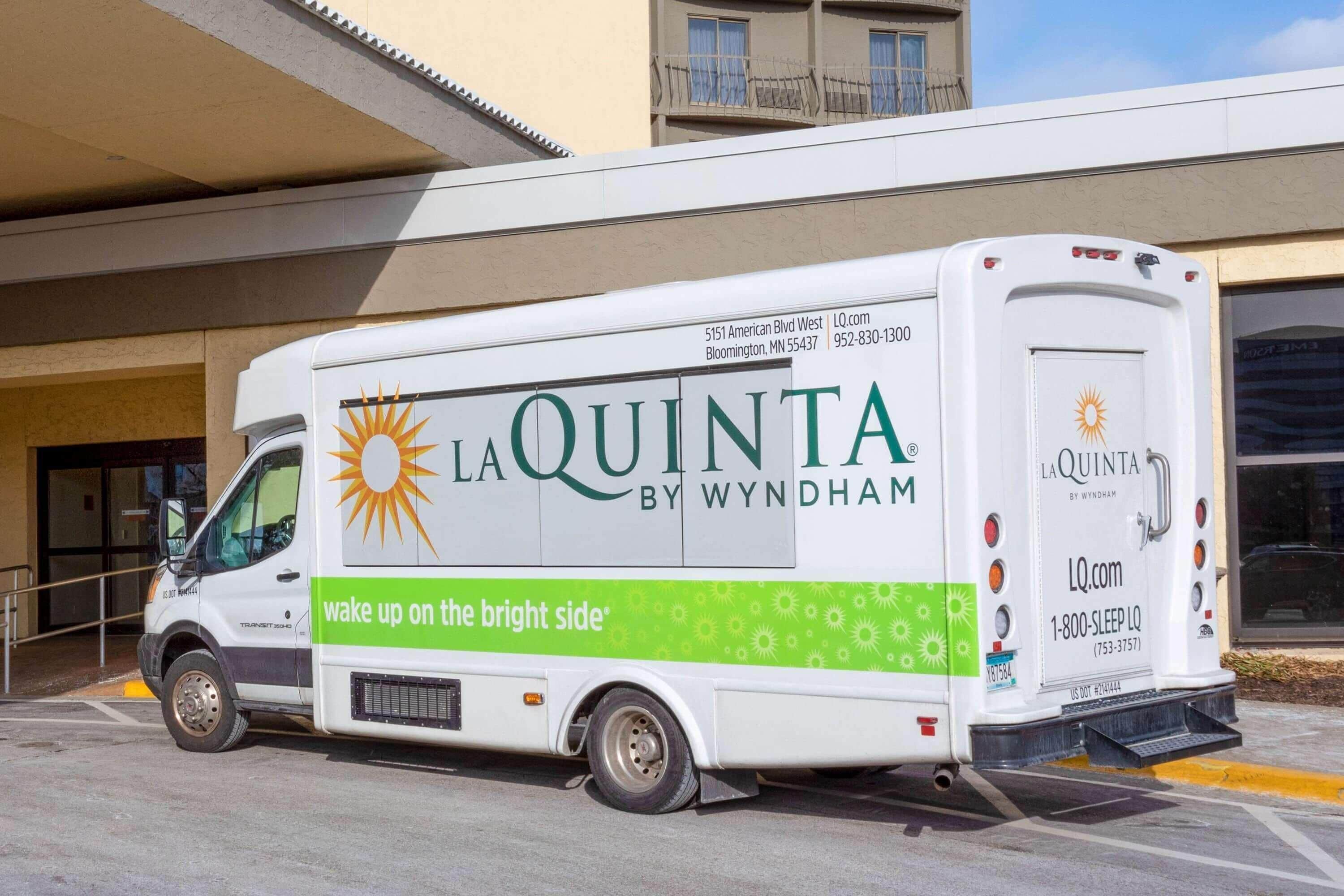 A white La Quinta by Wyndham delivery truck parked in front of a building.