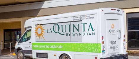 A white La Quinta by Wyndham delivery truck parked in front of a building.