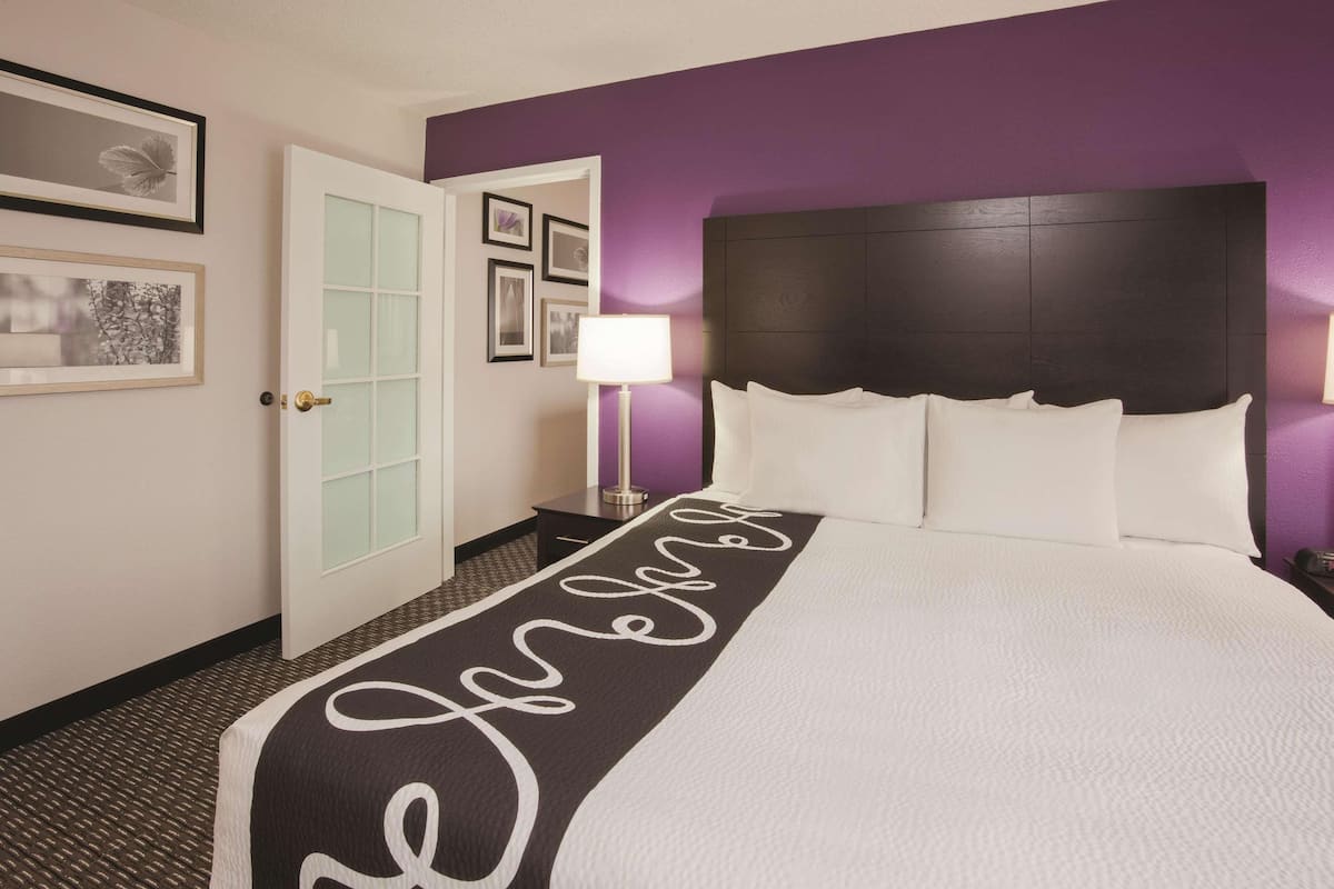 Habitació d'hotel amb un llit, una tauleta de nit, una làmpada i quadres a la paret.