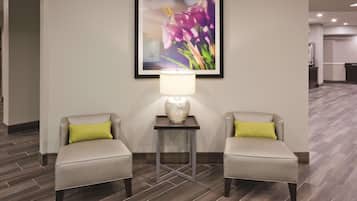 Un vestíbulo de hotel con dos sillones, una mesa con lámpara y una obra de arte floral enmarcada en la pared.
