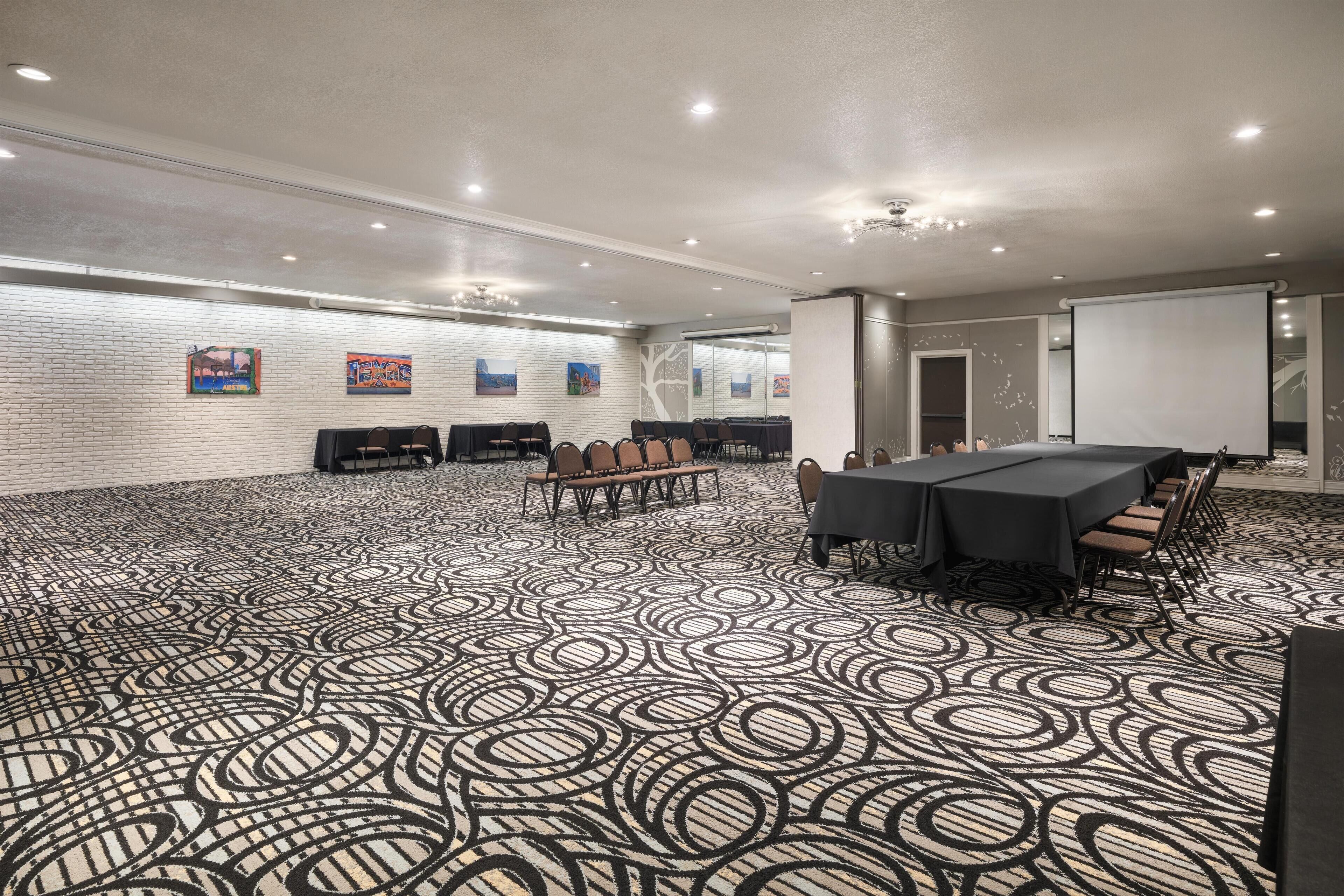 Una sala de conferencias con alfombra estampada, una mesa grande con sillas y una pizarra.