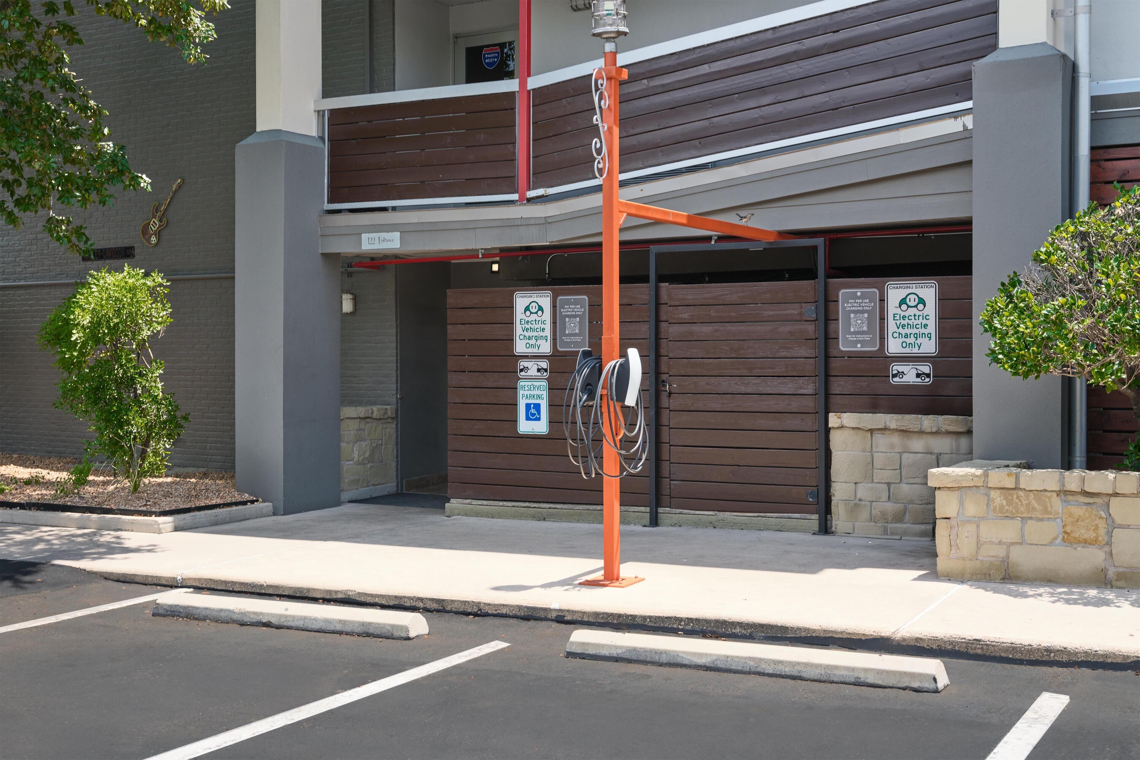 A building with a parking area, electric vehicle charging station, and a sign indicating reserved parking for disabled individuals.