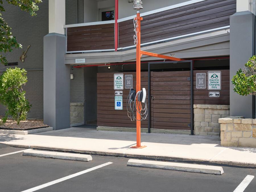 A building with a parking area, electric vehicle charging station, and a sign indicating reserved parking for disabled individuals.