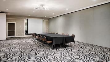 A conference room with a long table, chairs, and a projector screen.