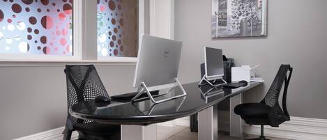 A conference room with a glass table, two black mesh office chairs, and two Dell laptops.