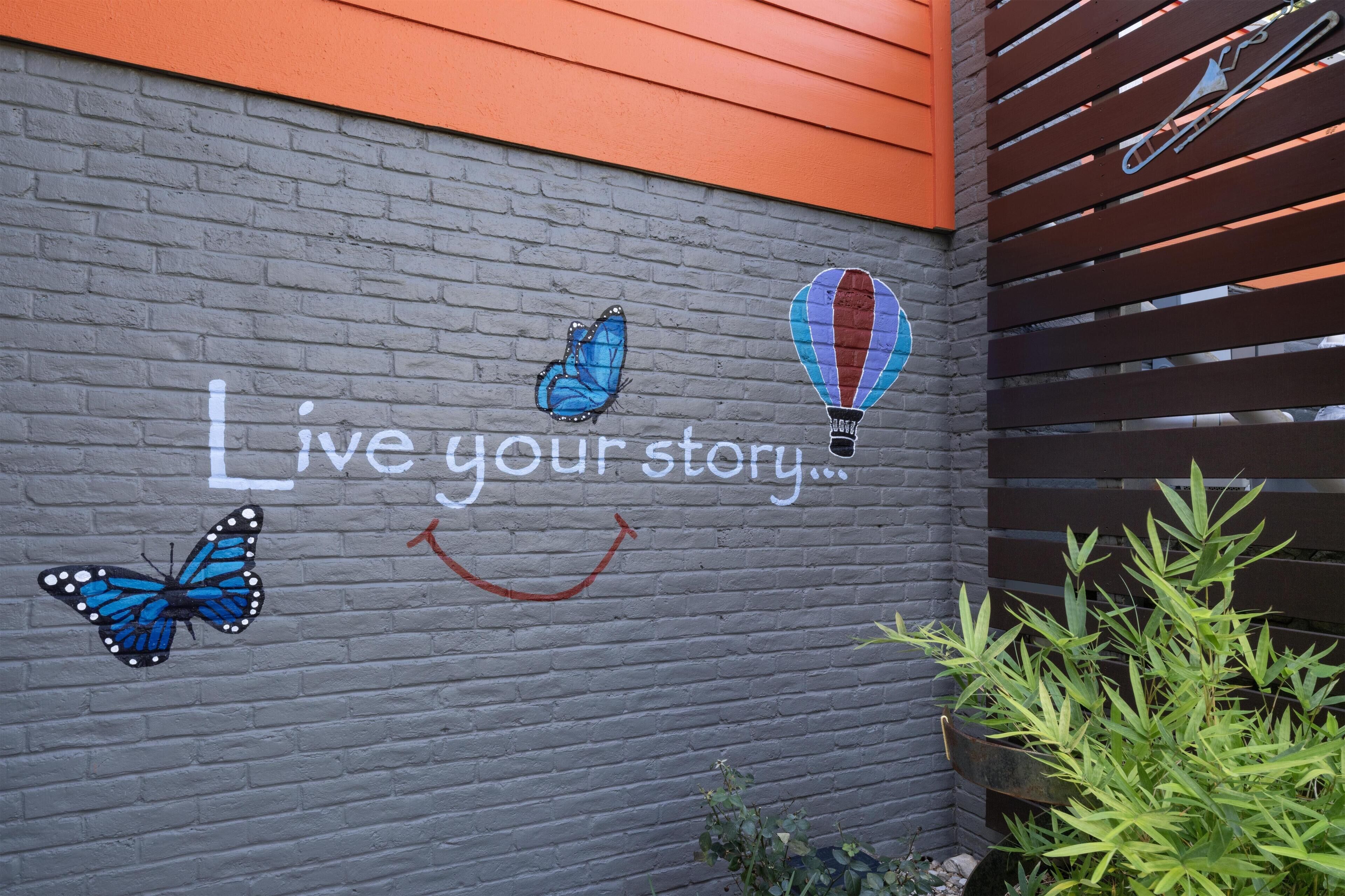 A wall with a motivational phrase, a butterfly, and a hot air balloon.