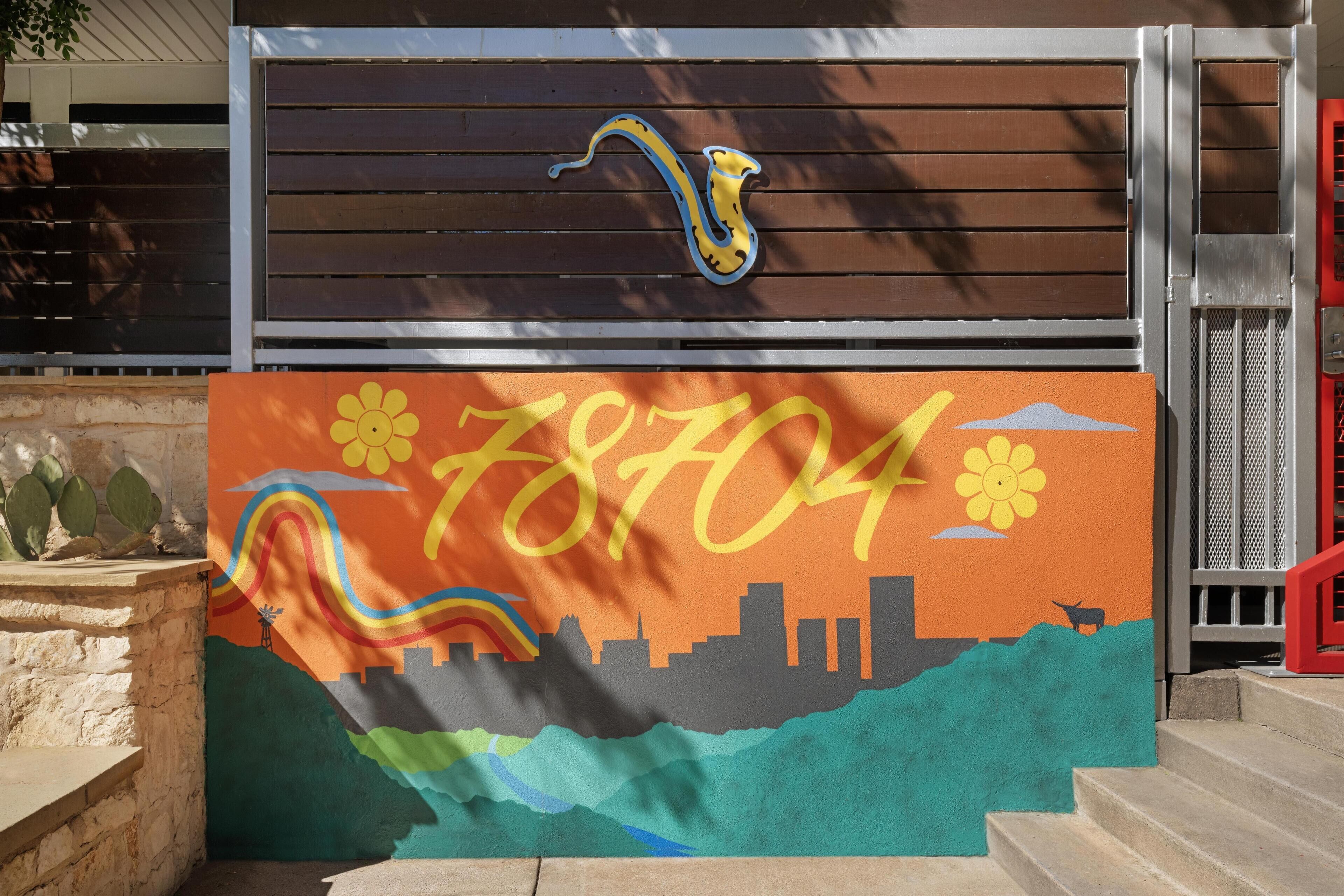 A colorful mural with a city skyline, a snake, and the number 78704.