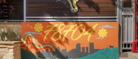 A colorful mural with a city skyline, a snake, and the number 78704.