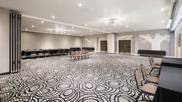 A conference room with a patterned carpet, multiple tables, chairs, and a ceiling with recessed lighting.