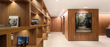 A modern interior with wooden shelving displaying books and a large framed photograph of a forest path.