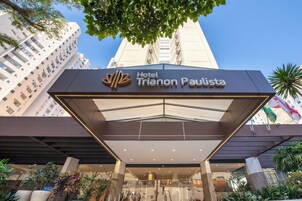 The entrance of Hotel Trionon Paulista with a modern design, featuring a glass facade and a prominent sign.