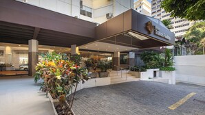 Een hotelingang met modern ontwerp, een overdekte doorgang en potplanten.