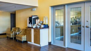 A hotel lobby with a reception desk, seating area, and a glass door leading to a dining area. - Comfort Inn & Suites (Moose Jaw)
