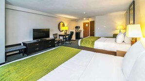A hotel room with two beds, a desk with a chair, a television, and a desk lamp. - Comfort Inn & Suites (Moose Jaw)