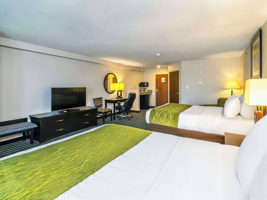Habitación de hotel con dos camas, un escritorio con silla, televisión y lámpara de escritorio.