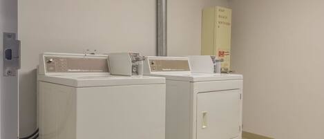 A laundry area with two front-loading washers and a cabinet labeled with laundry supplies.
