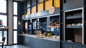 A modern café interior with a counter, shelves with cups and saucers, and a coffee machine. - B&B HOTEL Grenoble Centre Verlaine (Grenoble)