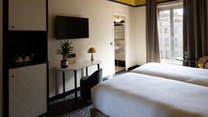 A hotel room with two beds, a TV, a small table with a lamp, a potted plant, and a view of the city. - Best Western Premier Hotel Roosevelt (Nice)