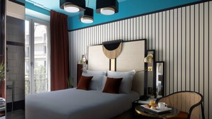 A hotel room with a large bed, a small table with a chair, a bedside lamp, and a view of the outside balcony. - Best Western Premier Hotel Roosevelt (Nice)