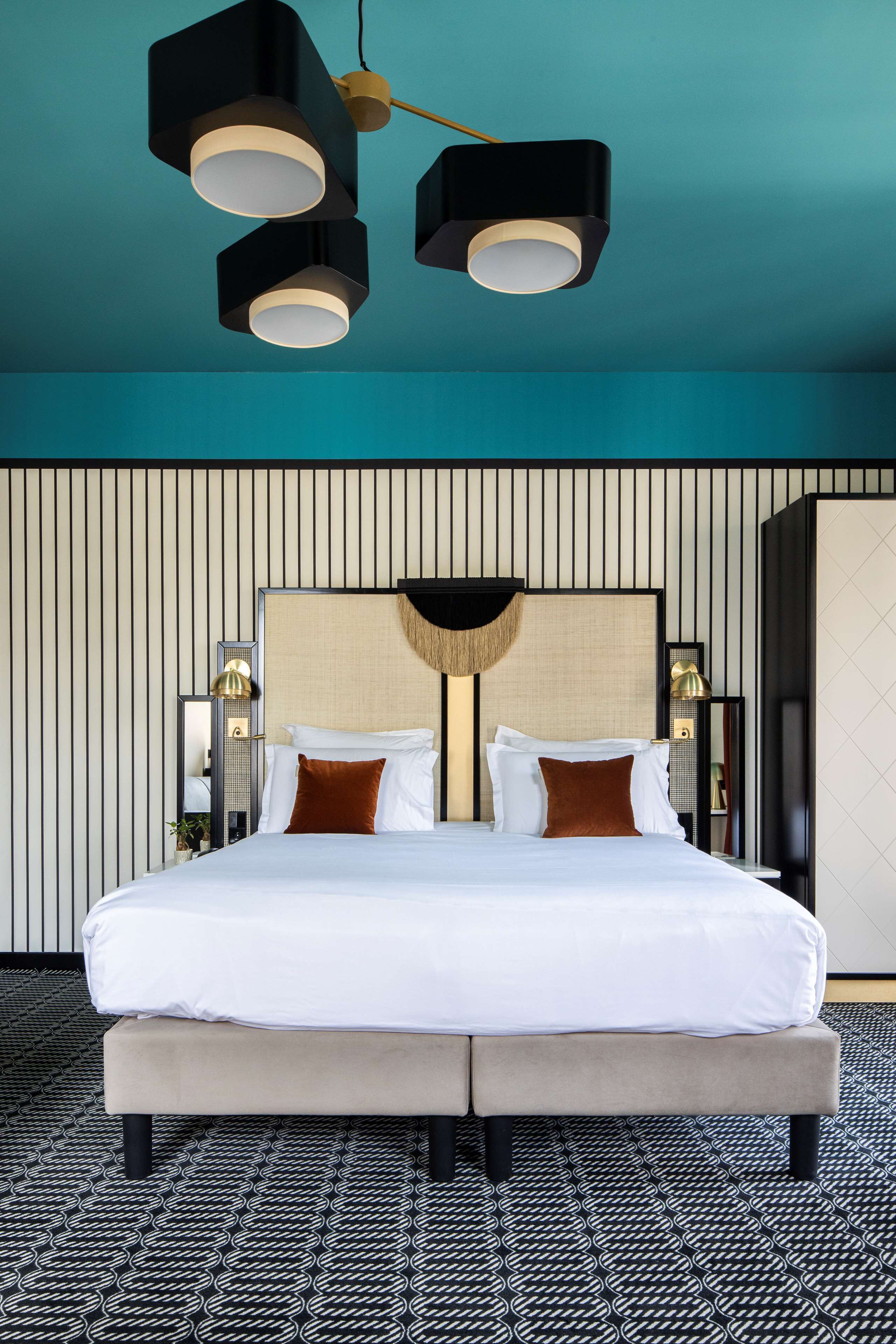 Een moderne hotelkamer met een groot bed, een bijzondere plafondlamp en een vloer met een patroon.