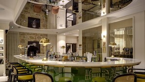 A spacious, multi-level bar area with a central island, green and yellow chairs, and a variety of bottles and glasses. - Best Western Premier Hotel Roosevelt (Nice)