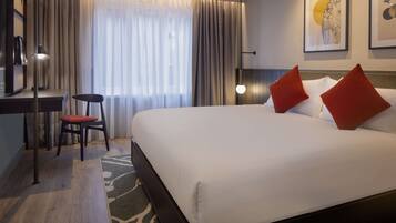 Una habitación de hotel con una cama grande, un escritorio y una silla.