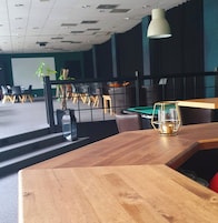 Un salón de conferencias con una pizarra, una pantalla de proyector y una mesa de billar.