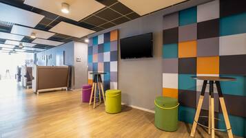 Relax in a modern space with a flat-screen TV, colorful checkered walls, and a wooden floor.