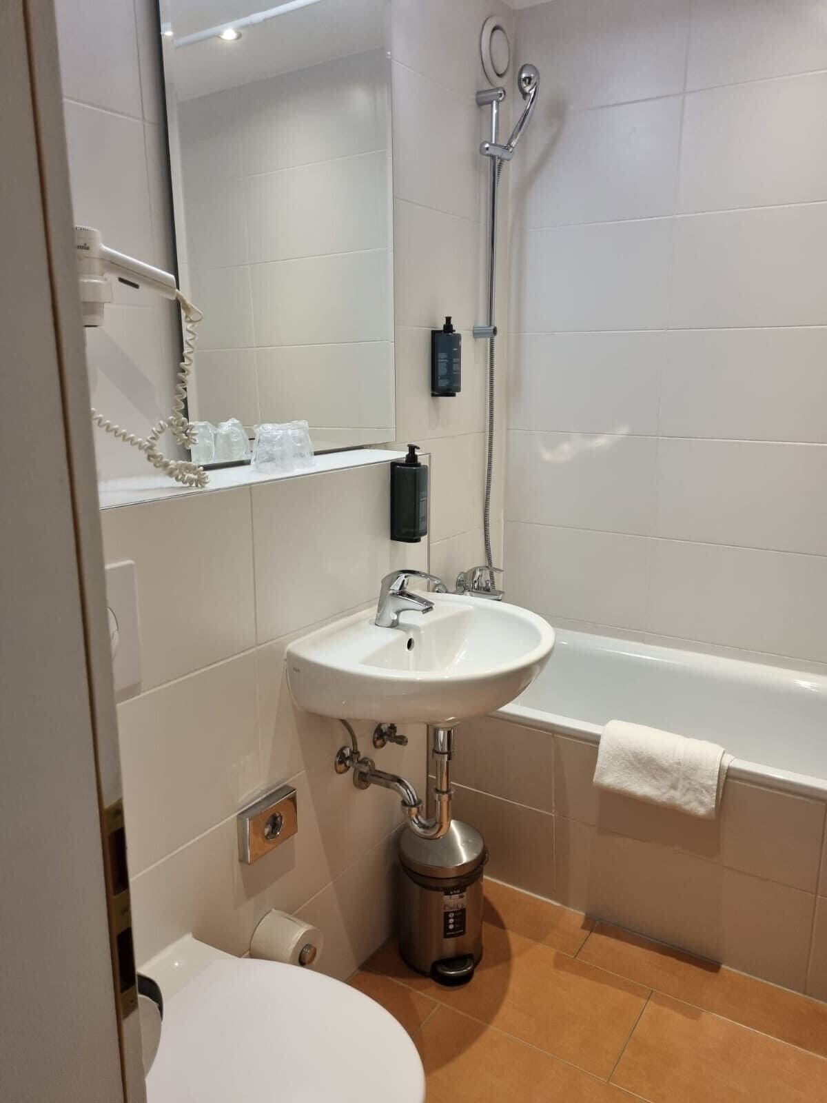 Kylpyhuone, jossa on valkoinen pesuallas, wc-istuin, suihku ja kylpyamme.
