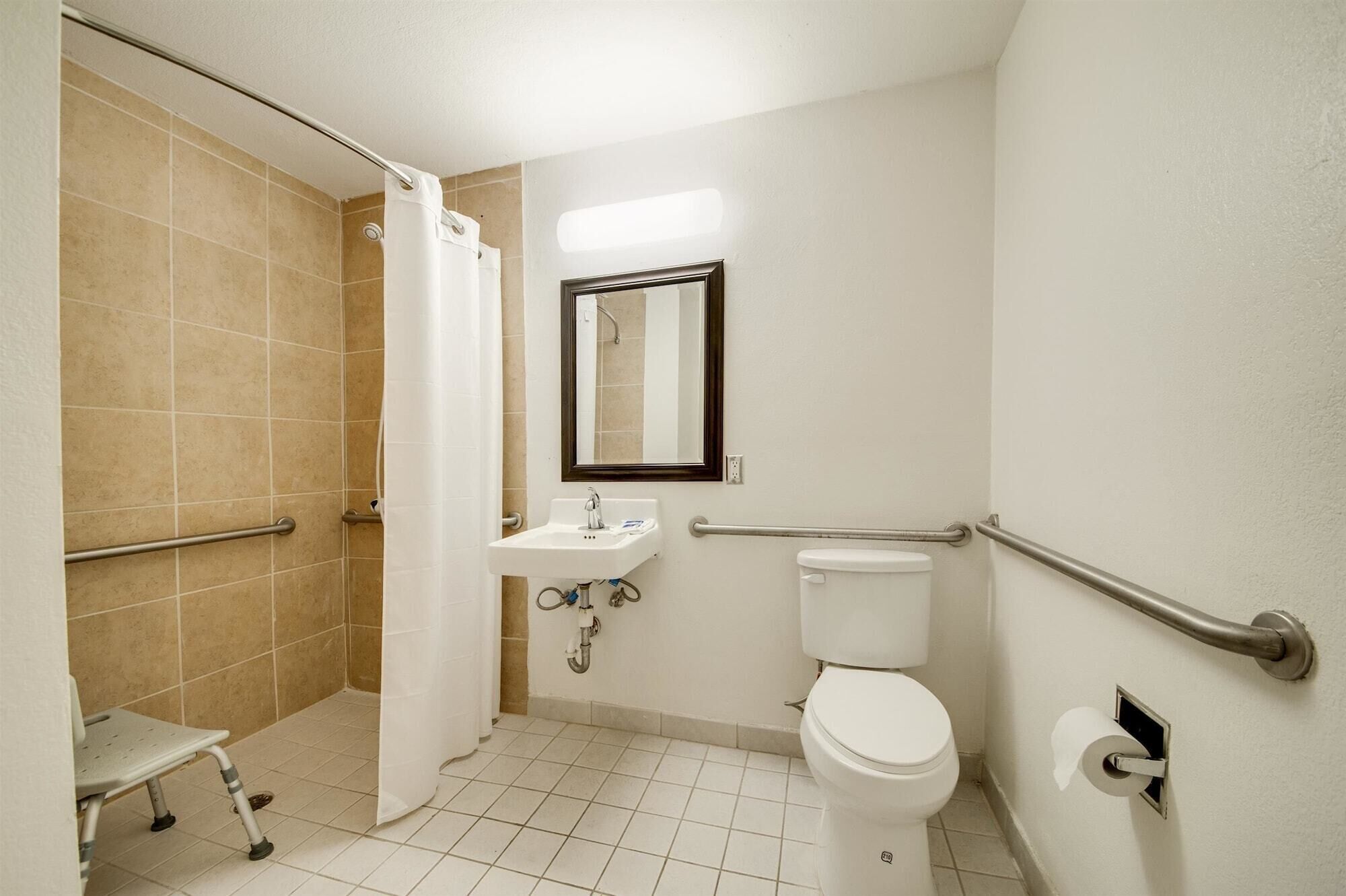 Une salle de bain équipée d’une douche, de toilettes, d’un lavabo et d’une barre d’appui.
