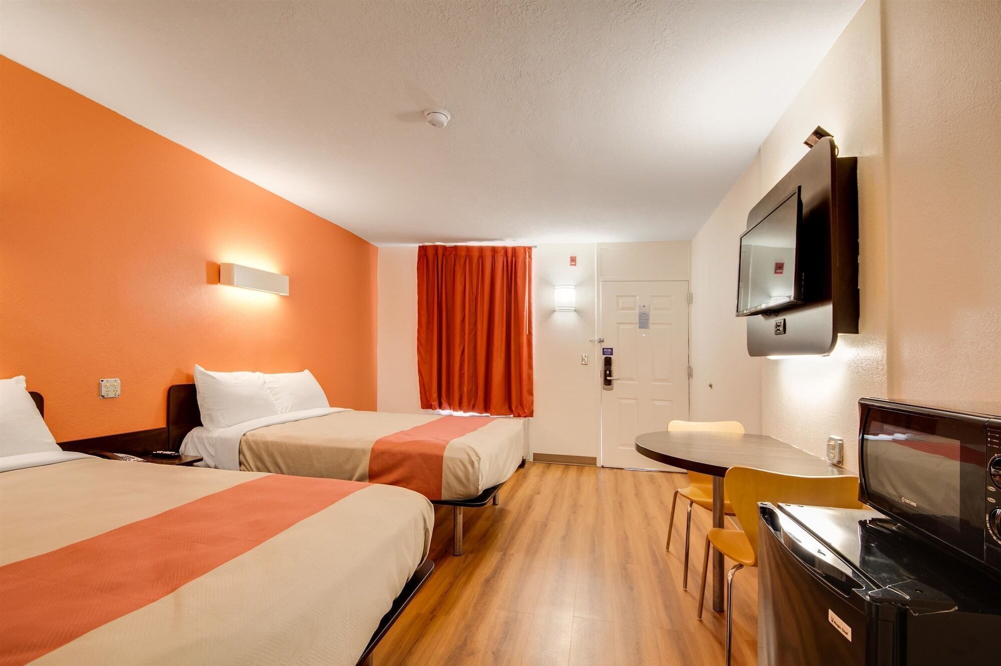 A hotel room with two beds, a TV, a desk, and a chair.