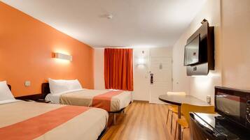 A hotel room with two beds, a TV, a desk, and a chair.