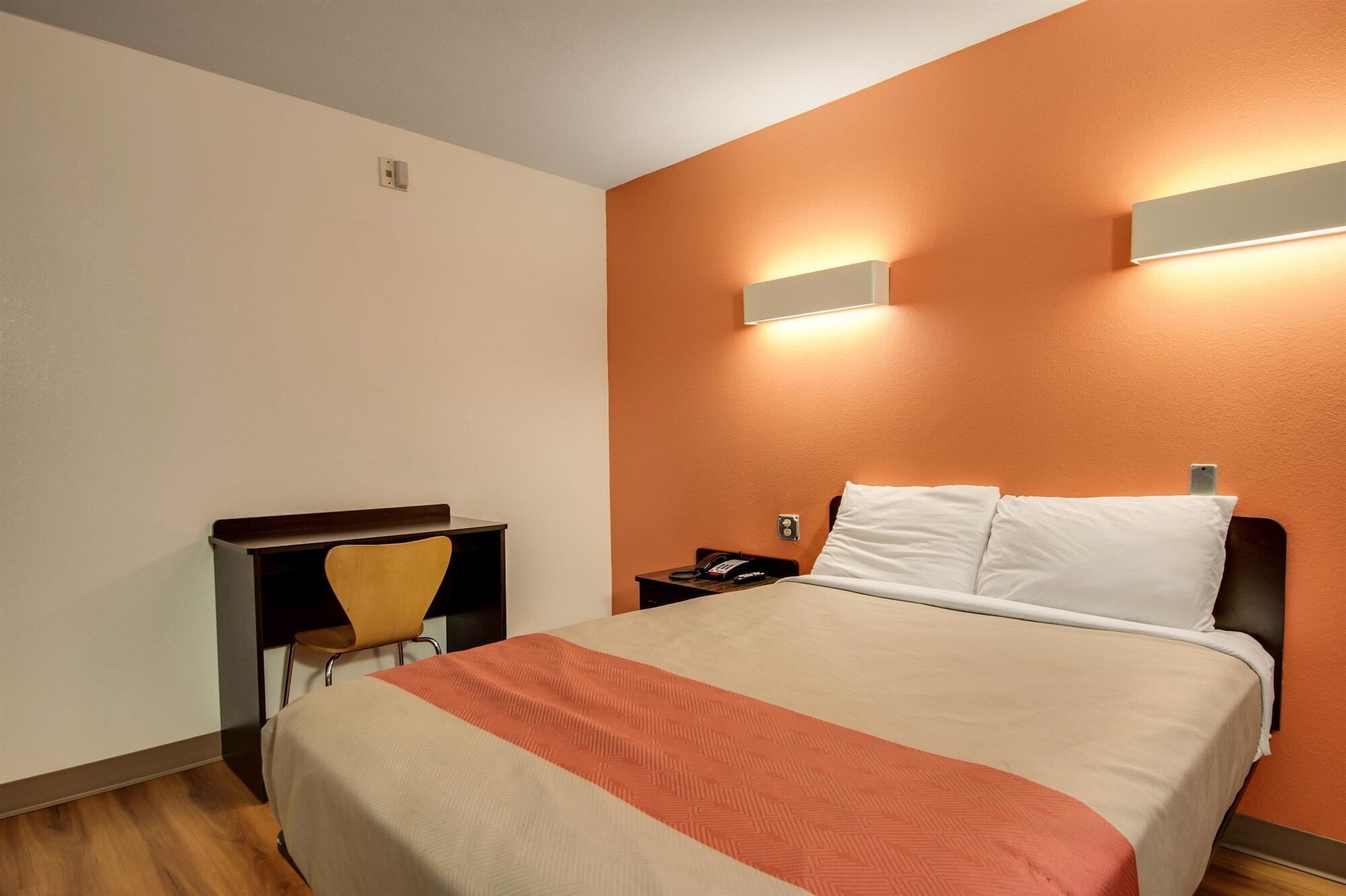 A hotel room with a bed, a desk, and a chair.