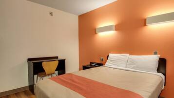 A hotel room with a bed, a desk, and a chair.
