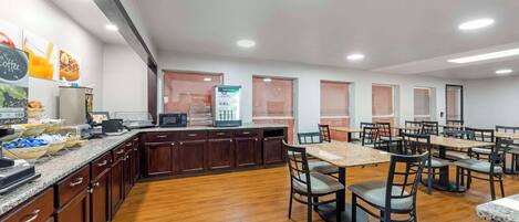 A spacious dining area with wooden flooring, dark wooden cabinets, and multiple tables and chairs.