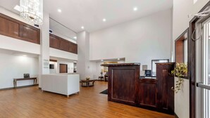 A spacious lobby with a wooden reception desk, a white reception area, and a high ceiling with recessed lighting. - Quality Inn El Reno (El Reno)