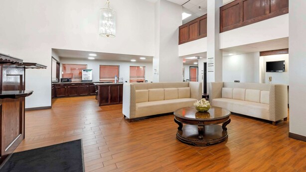 A spacious living area with a wooden floor, a beige sofa, a round coffee table, and a kitchen in the background. - Quality Inn El Reno (El Reno)
