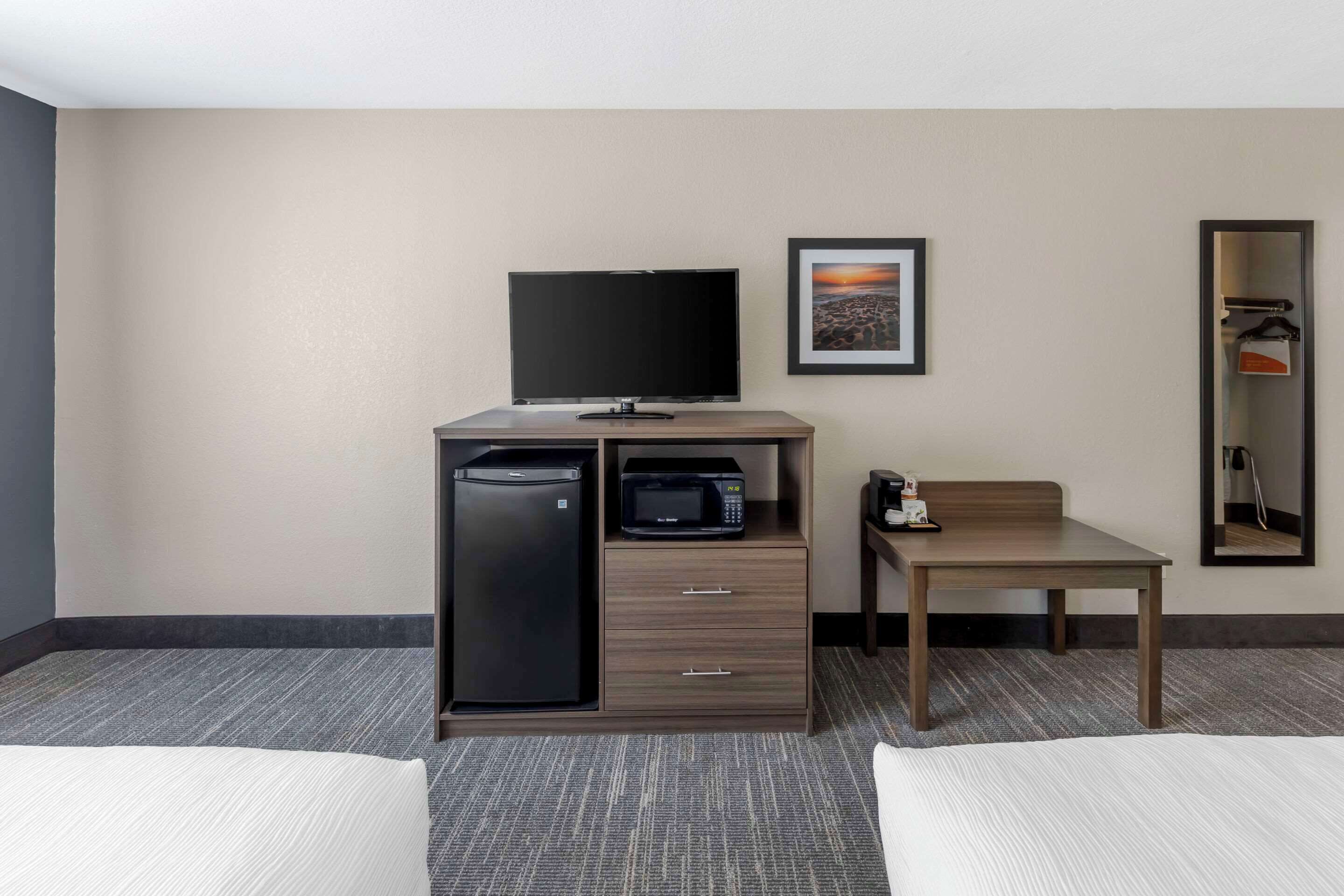 Une chambre d’hôtel comprenant un lit, un bureau avec un micro-ondes, une télévision et un petit placard.