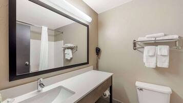 A bathroom with a large mirror, a sink, a toilet, and a towel rack.