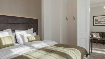 A neatly made bed with a headboard, a white door, and a framed picture on the wall.