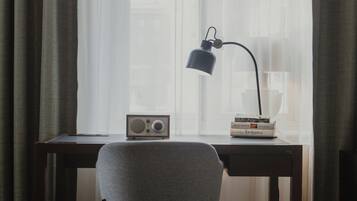 Una habitación con escritorio, silla, radio y lámpara.