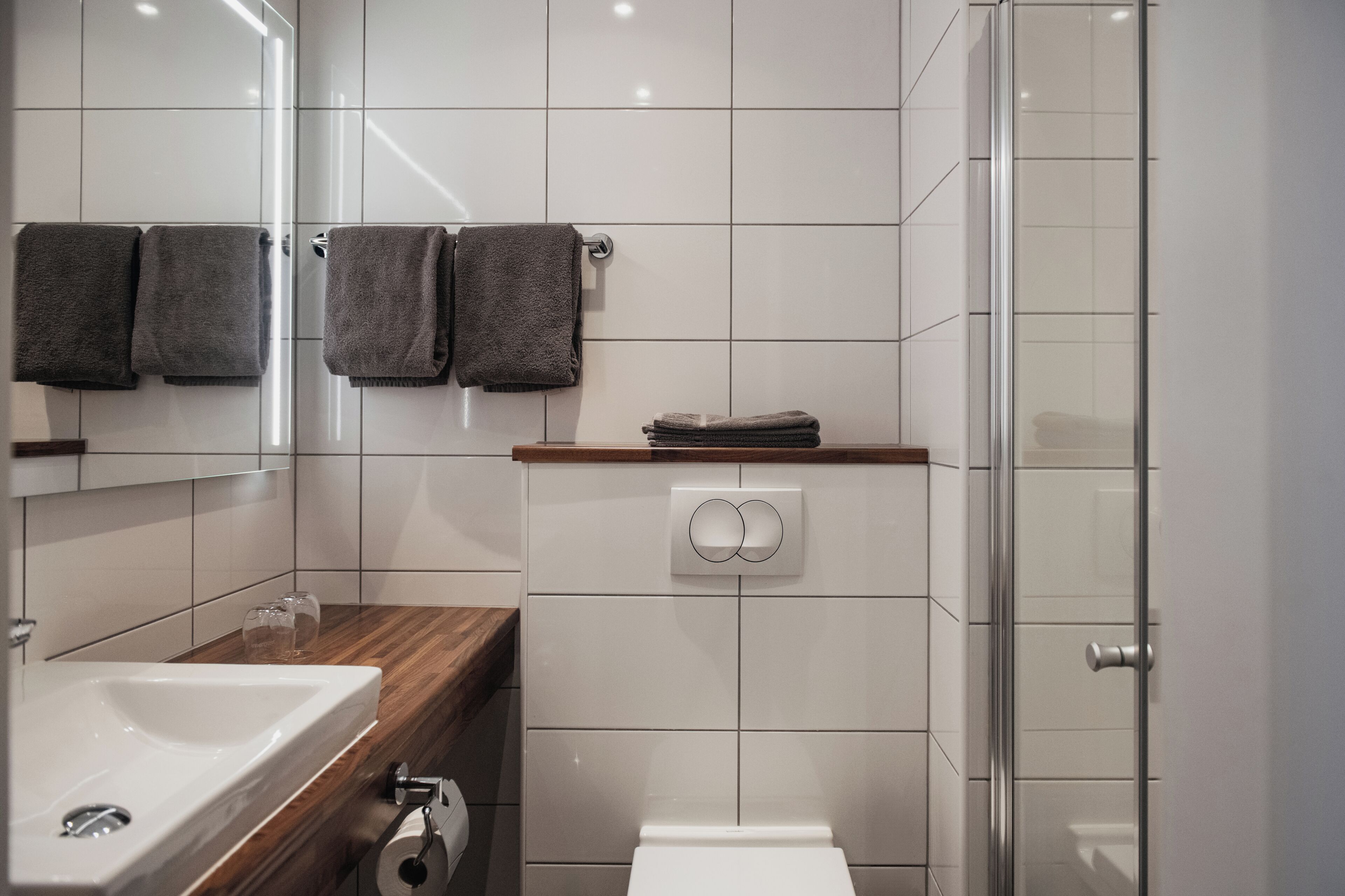 A modern bathroom with a sink, mirror, towel rack, toilet, and shower.