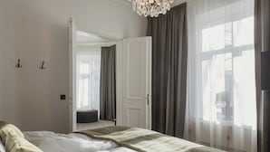 A bedroom with a bed, a door, a chair, and a window with curtains.