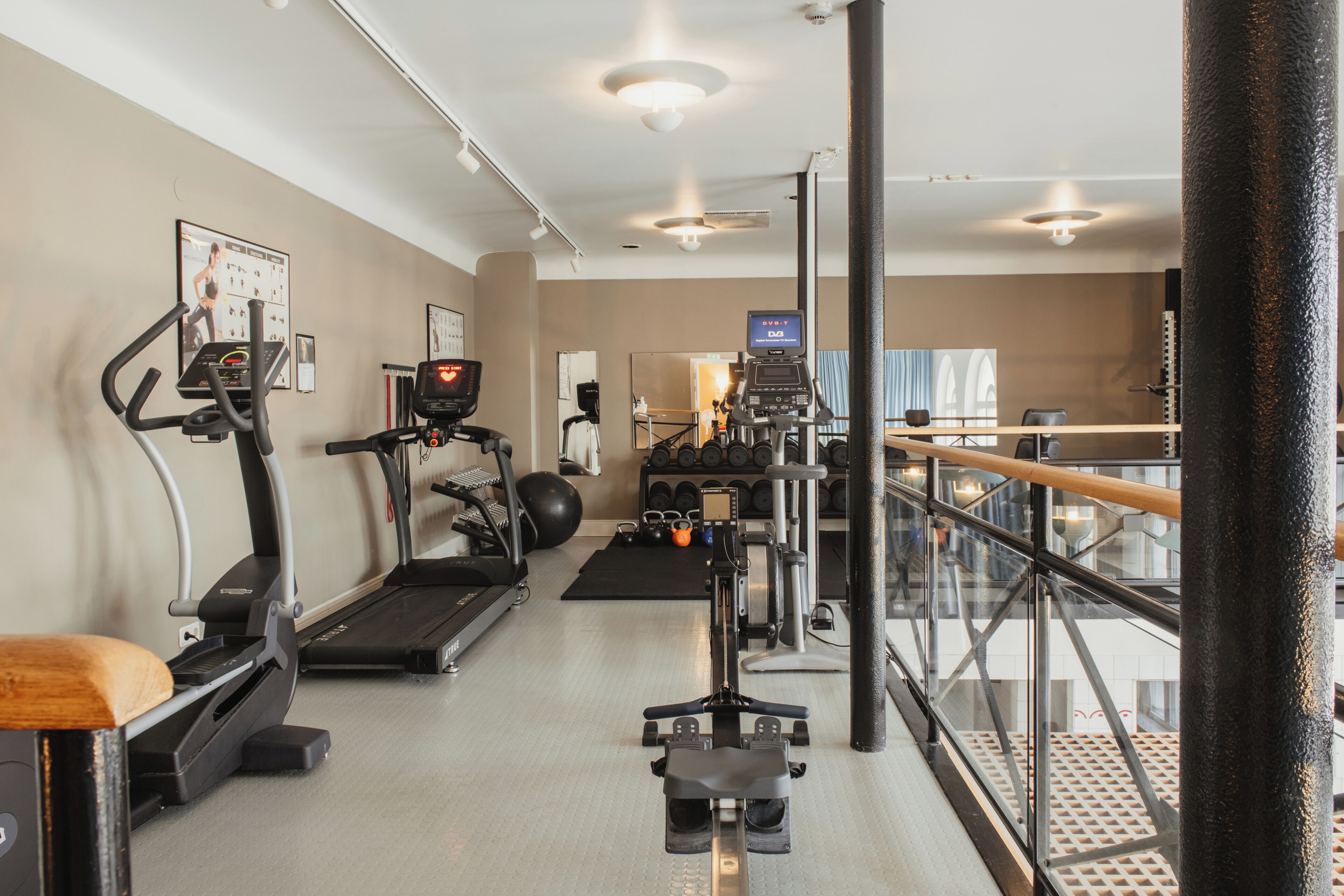 Uma academia com esteiras, remo e equipamentos de musculação.