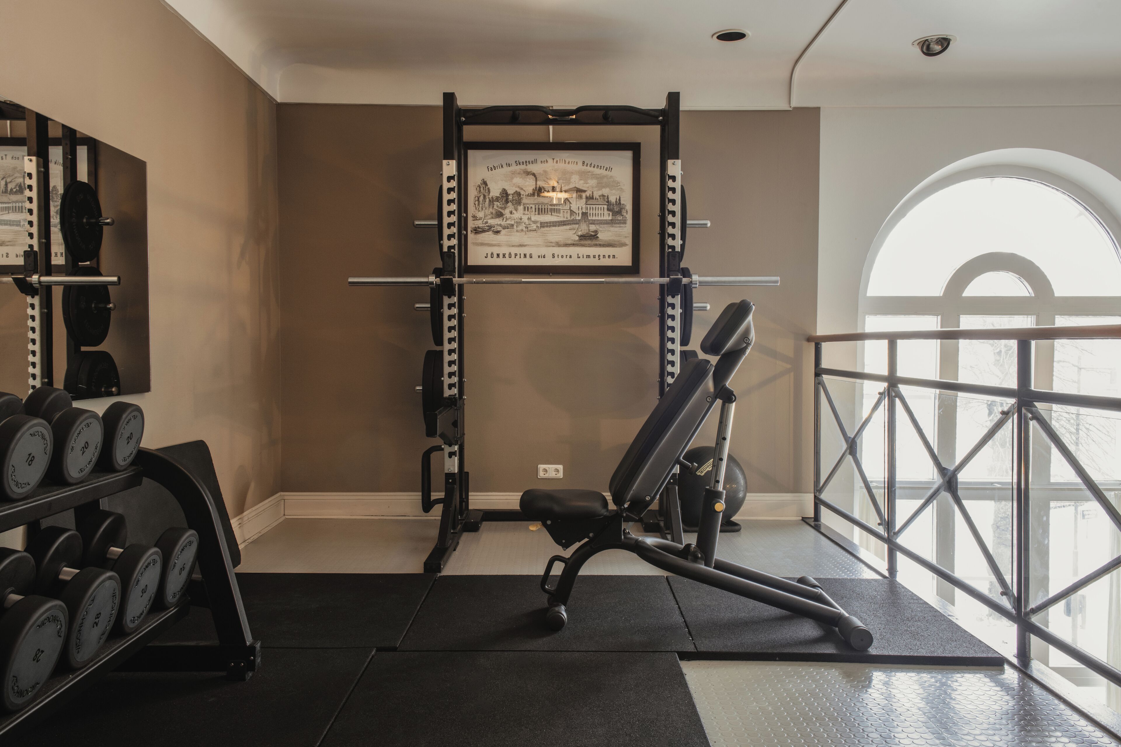 A gym with weightlifting equipment, a bench, and a framed picture on the wall.